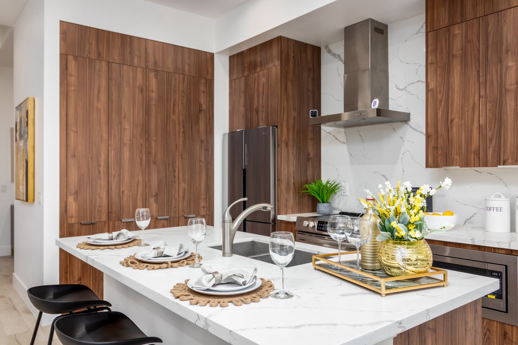 Kitchen with waterfall quartz island, walnut cabinetry, and stainless appliances